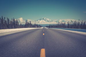route déserte en face d'une montagne enneigée alaska